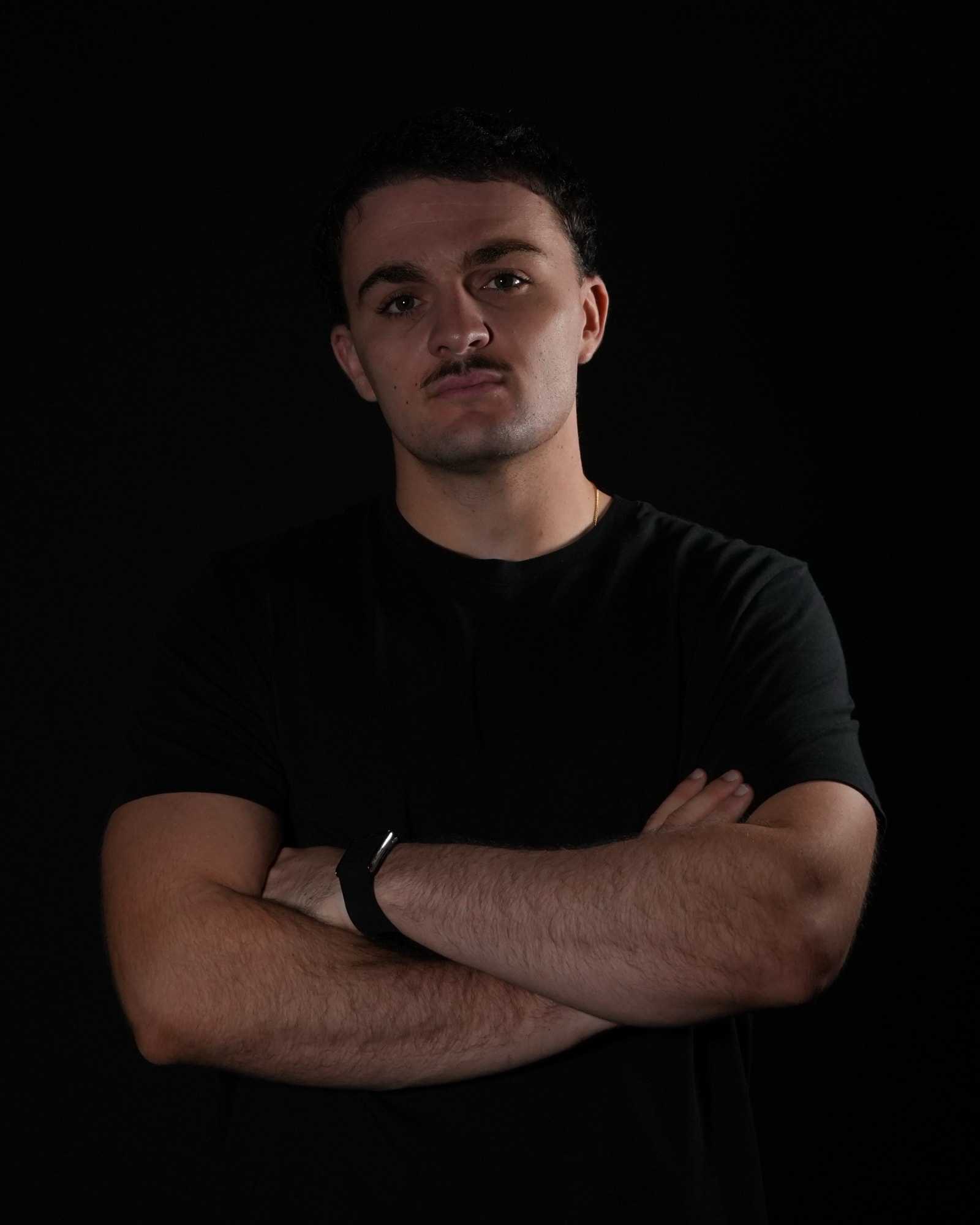 Portrait de Yoan Hibert, expert IA chez StratIA, bras croisés sur fond noir.